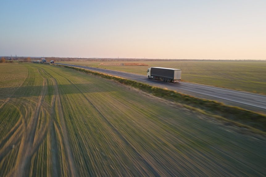 Lorry driving on the road passed some fields